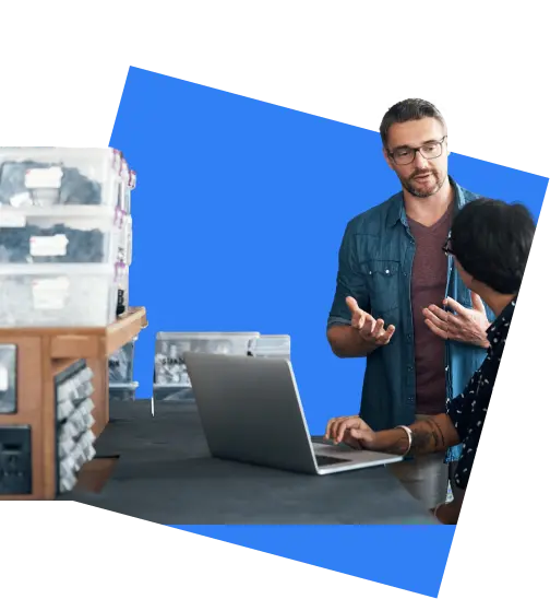 Business owners talking over a laptop in a storeroom