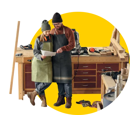 Two carpenters reading a document in their workshop