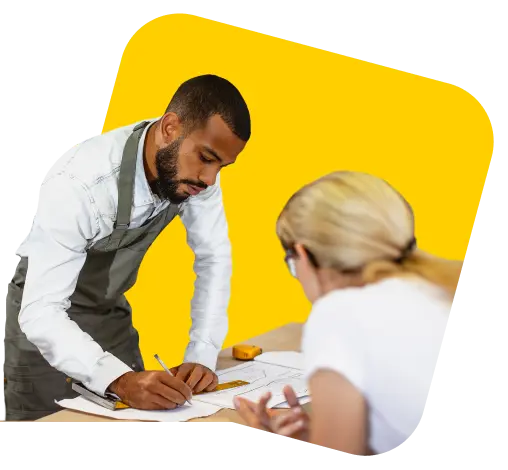 Two colleagues going through plans at a workbench