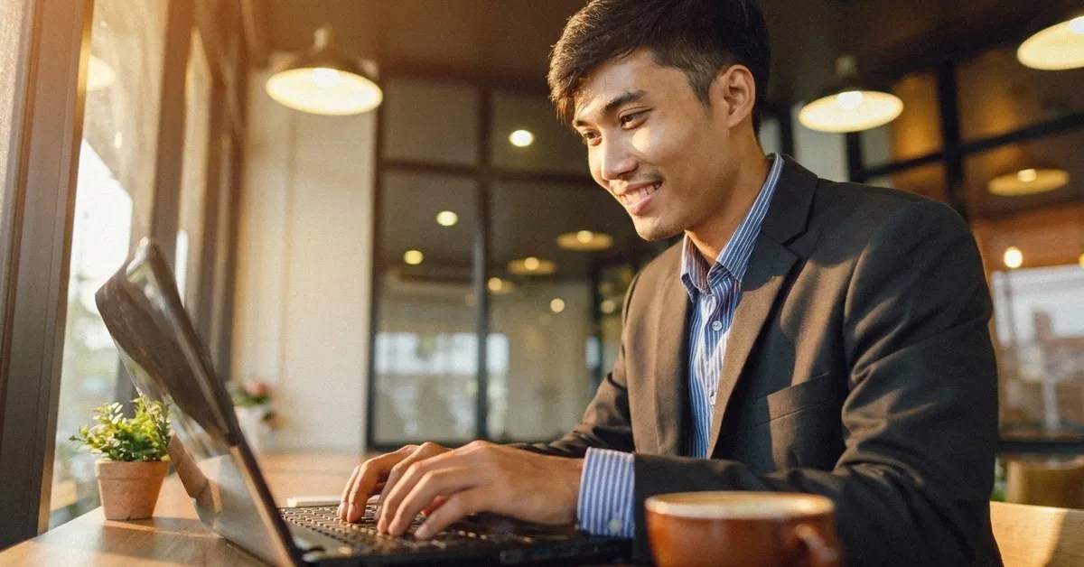 A Filipino man sits at the table looking at his laptop reading about the UK visa for Filipinos process