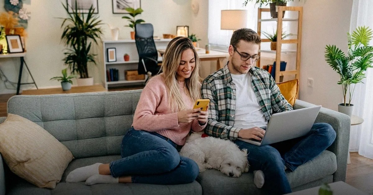 A young man and woman sit on a sofa and look at a laptop reading about the best Wise alternatives